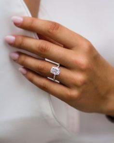 a woman's hand with a diamond ring on her left hand and a white shirt