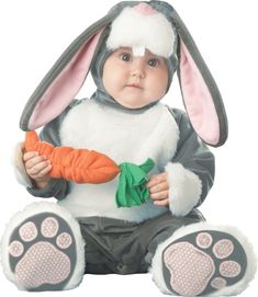 a baby dressed as a bunny holding a carrot