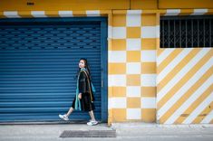 a woman standing in front of a blue garage door with yellow and white stripes on it