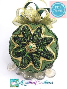 a green ornament with gold trim and a bow on it's side