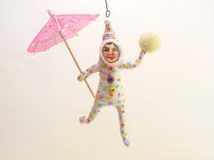 a toy doll hanging from a string with an umbrella and pom - pom