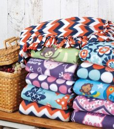 a pile of colorful towels sitting on top of a wooden shelf next to a basket