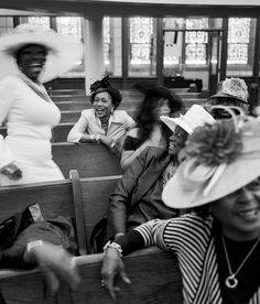 black and white photograph of women in church pews with hats on their heads, smiling