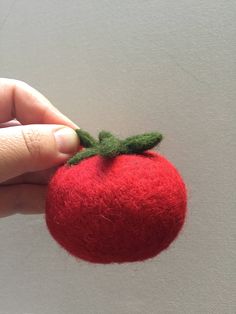 a hand holding a needle felt strawberry