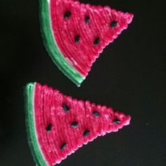 two pieces of watermelon sitting on top of a black table next to each other