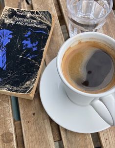 a cup of coffee sitting on top of a wooden table next to an old book