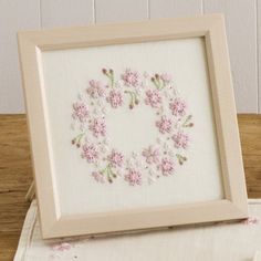 a white frame with pink flowers in it on a table next to a wooden box