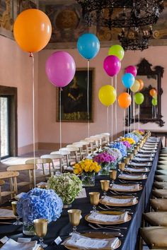 a long table is set up with balloons and place settings