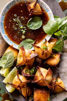 a plate with some food on it next to a bowl filled with sauce and garnishes