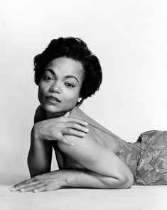 a black and white photo of a woman laying on the floor with her arms crossed