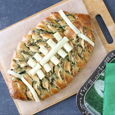 a piece of bread with cheese and spinach on it next to a knife and fork