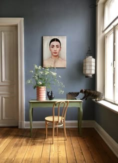 a room with blue walls and a painting on the wall next to a green table