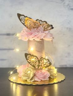 a cake decorated with flowers and butterflies on a plate, lit up by fairy lights