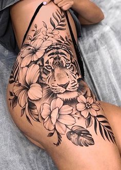 a woman laying on top of a bed covered in flowers and a tiger tattoo design