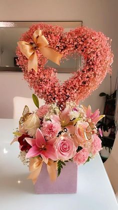 a heart shaped arrangement with pink flowers on a table