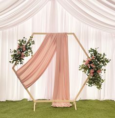 a wedding arch decorated with pink flowers and greenery