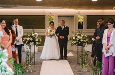 a bride and groom standing at the end of their wedding ceremony with other people watching