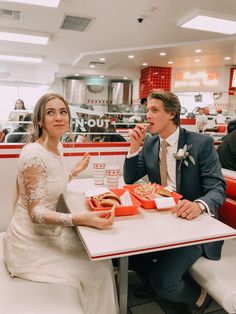 a man and woman sitting at a table eating hot dogs