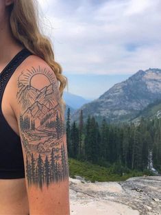 a woman with a mountain scene tattoo on her arm and shoulder, looking at the camera