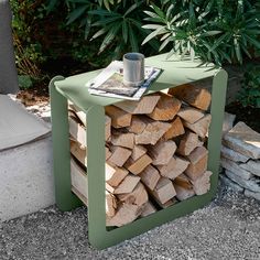 a table made out of wood with a cup on it and some plants in the background