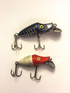 two fishing lures hanging from hooks on a wall