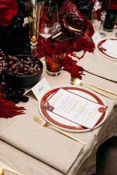 the table is set with red and gold place settings