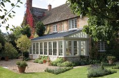 a large house with lots of windows and plants in the front yard, surrounded by greenery