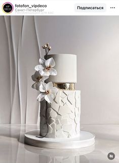 a three tiered cake with white flowers on it's side and gold accents