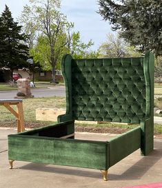 a green velvet bed frame sitting on top of a sidewalk