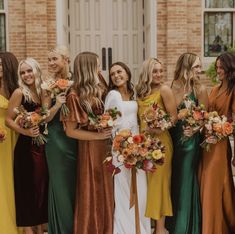 a group of women standing next to each other wearing dresses and holding bouquets in their hands