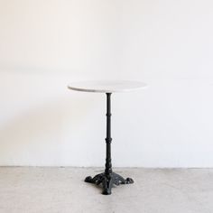 a white table sitting on top of a cement floor next to a wall with a black pipe sticking out of it