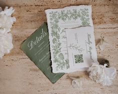 the wedding stationery is laid out on the table with white flowers and greenery