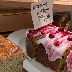 a piece of cake with raspberry topping on it and a loaf of bread in the background