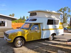 a yellow and white camper parked in front of a house