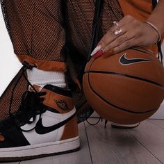 a close up of a person holding a basketball on the ground with their shoes off