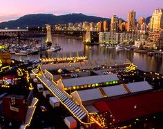 an aerial view of a city at night with lights on buildings and boats in the water