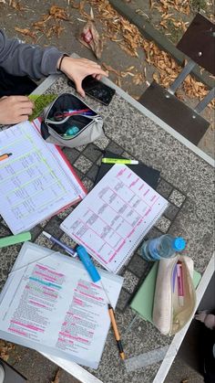 a person sitting at a table with notebooks and pens on it next to a cell phone