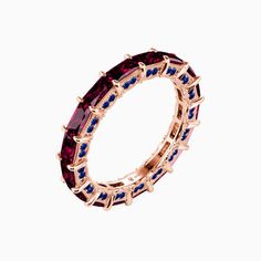 a gold ring with blue and pink stones on it's sides, set against a white background