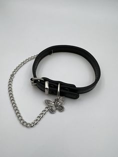 a black leather bracelet with a butterfly charm hanging from it's center, on a white background