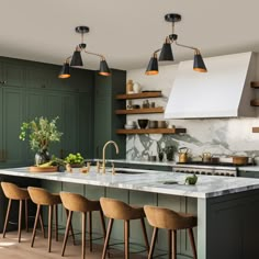 a kitchen with green cabinets and marble counter tops, wooden stools and hanging lights