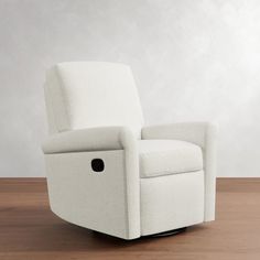 a white recliner chair sitting on top of a wooden floor next to a wall