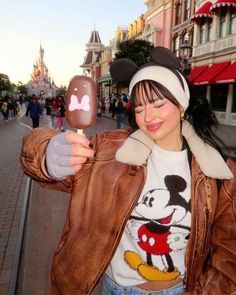 a woman holding an ice cream in front of a mickey mouse character on the street