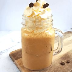 a glass mug with whipped cream and chocolate chips in it sitting on a cutting board