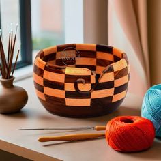 a wooden bowl sitting on top of a table next to yarn