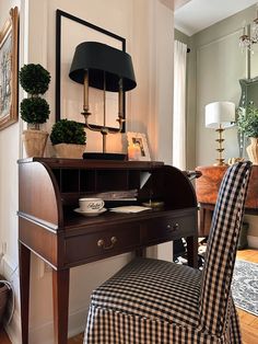 a desk with a chair, lamp and pictures on the wall