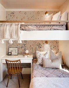 a bedroom with two bunk beds and a desk in front of the bed is made up