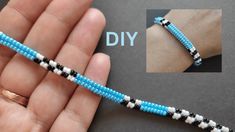 a hand holding a blue and white beaded bracelet