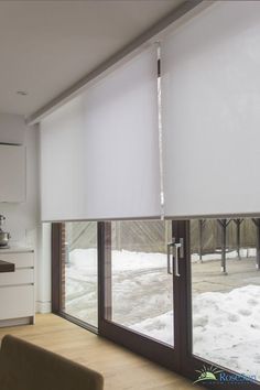 a living room filled with furniture and windows covered in white roman blind coverings on the sliding glass doors