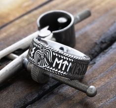 two silver rings sitting next to each other on top of a wooden table with wrenches