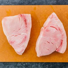 two pieces of raw meat sitting on top of a cutting board